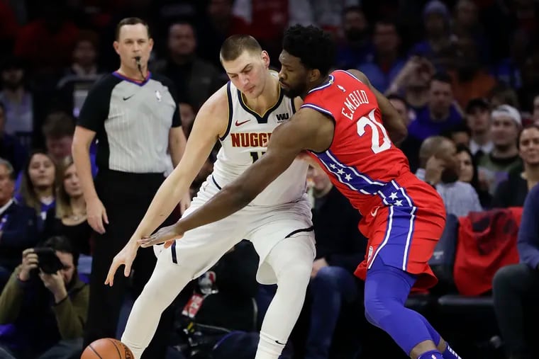 Sixers center Joel Embiid reaches for the basketball against Denver Nuggets center Nikola Jokic during the first-quarter on Friday, February 8, 2019 in Philadelphia.