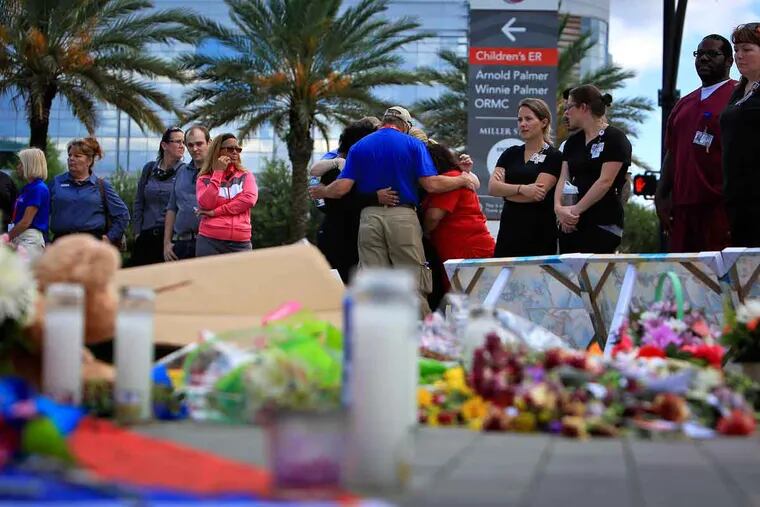 Carl Hill, from the Billy Graham Rapid Response Team, prays with a group of women near a memorial for the victims of the Pulse nightclub shooting set up at the Orlando Health sign Thursday, June 16, 2016, in Orlando, Fla.