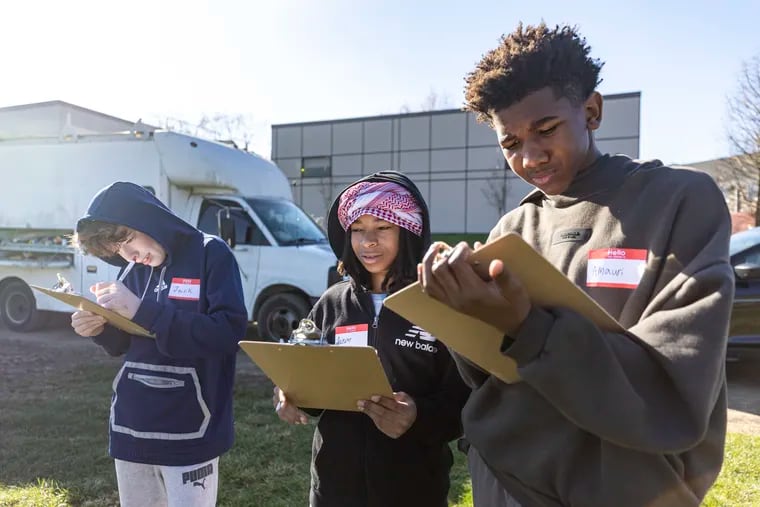 Jack Akins (from left), 13, of East Falls, a seventh grader; Aazim Drayton, 12, of South Philadelphia, a sixth grader; and Amauri Henry, 13, of North Philadelphia, a seventh grader, are working on a hypothesis on what researchers are trying to learn using solar panels in growing fruits and vegetables at Temple University's Ambler campus.
