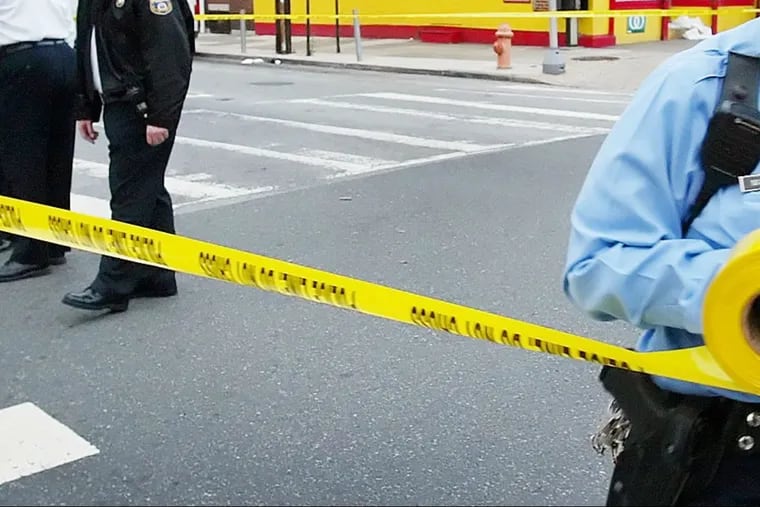 Philadelphia police run crime scene tape.