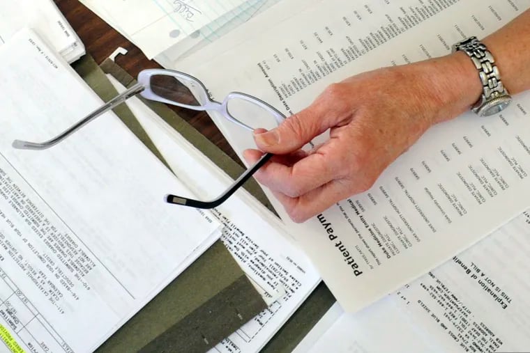 Medical bills and other records are spread out on the kitchen table of a patient in Salem, Va.