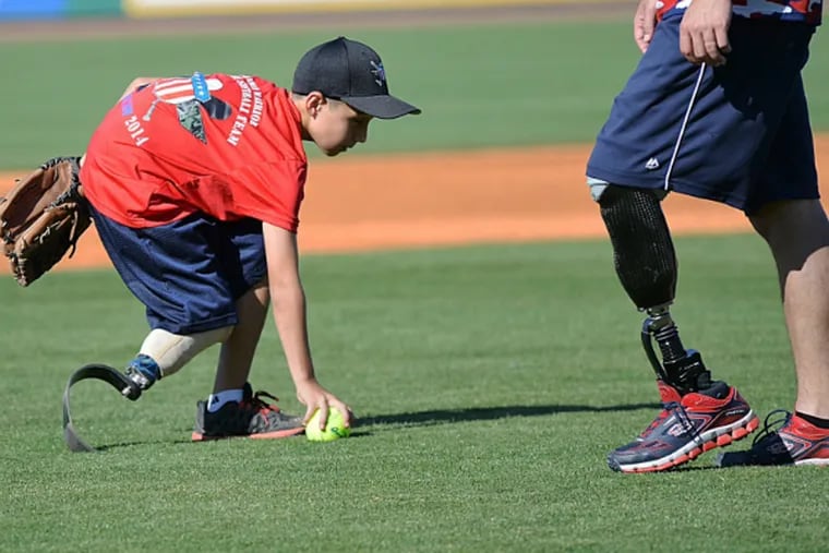 Adrian Grajeda fields the ball with a wounded warrior nearby. (Photo: Wounded Warrior Amputee Softball Team)