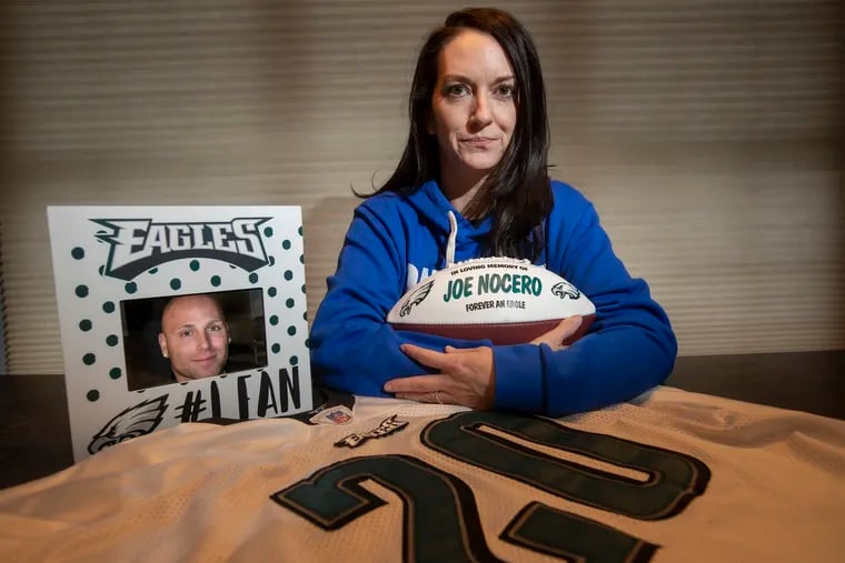 Melissa Nocero, in her Jamison home, with the ball the Eagles organization gave her family with her husband Joe Nocero’s name painted on it; her husband’s favorite player's jersey, #20 Brian Dawkins; and his photo in a frame that a friend gave her after his death.  Joe Nocero died during the Eagles-Patriots game on Nov. 17, 2019. He was 41.