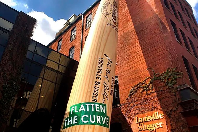 In this April 7, 2020, photo provided by Louisville Slugger Museum & Factory, a “Flatten the Curve” banner adorns the 120-foot Big Bat outside Louisville Slugger Museum & Factory in Louisville, Ky., in an effort to help spread the "stay healthy at home" message and bring down the number of COVID-19 cases.