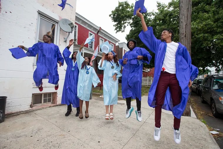 (L-R):  Saliekee Roberts, Derrick Reed, Christelle Christpin, Vanessa Macias-Olivares, Daniel Noel, and Nasir Smith- Rafi celebrate on June 16, 2020. Madeline Birkner (not pictured) is a college access coordinator with the non-profit Philadelphia Education Fund working out of Olney Charter High School. She will be offering her seniors the opportunity to receive their customary College Access graduation medallion at their homes along with a photo.  “There is something special about having a nice photo of yourself in your cap and gown,” she says.  “Plus, I I got to see the students in person and celebrate the moment with them…It’s exhausting, but so worth it to see them with their families.” Over 50 seniors signed up to have their photos taken at home or in front of the high school.”