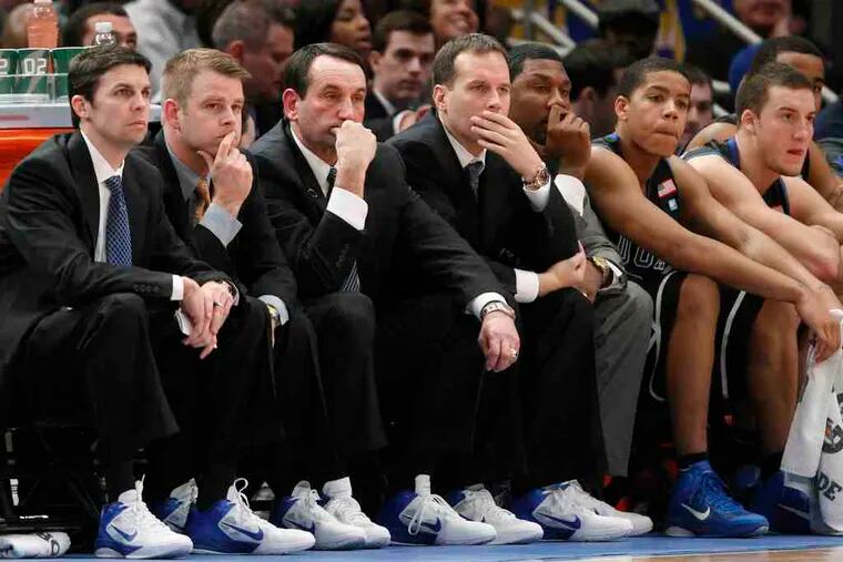 Duke coach Mike Krzyzewski (third from left), sits glumly with his staff and players during the Blue Devils' loss to St. John's.
