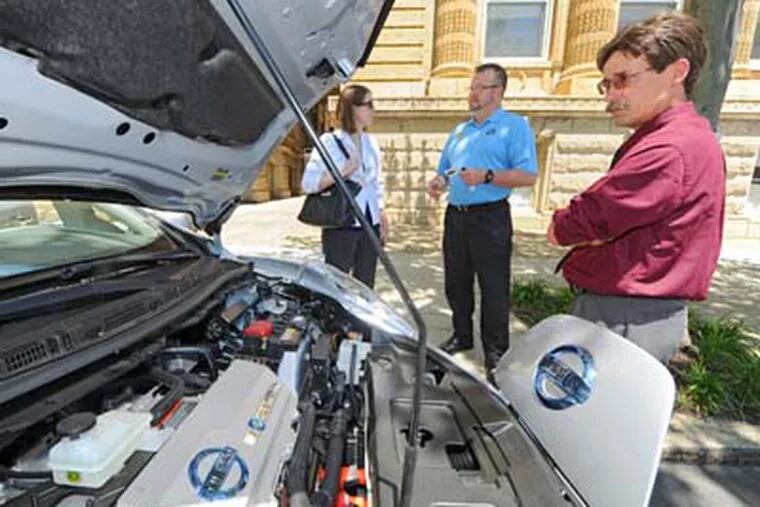 The Pennsylvania Public Utilities Commission holds a day-long conference on alternative fuel vehicles at Drexel University and has some examples parked outside for the curious to peruse Thursday, May 31, 2012.  Eric Jespersen (right), an analyst for New York company Fisher Associates, looks at the engine compartment of a Nissan Leaf as Lincoln Overholtzer (center) from Exton Nissan talks with Alexis Williams, an environmental planner for Baker Engineers of Philadelphia  ( CLEM MURRAY / Staff Photographer )