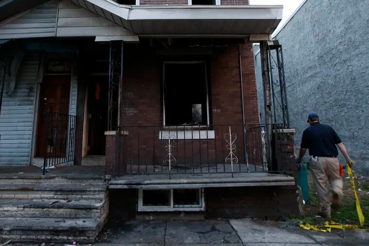 An L & I worker takes down crime scene tape after a hit-and-run and a house fire on the 4400 block of Wingohocking St., in the Nicetown neighborhood of Philadelphia on April 17, 2015.  ( Yong Kim / Staff Photographer )