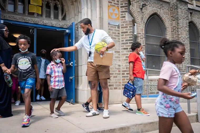 Trent Petty, the site leader for the Freedom School Literacy Academy at Mastery Prep Charter, comforts a crying child, as students exit the building to participate in recess.