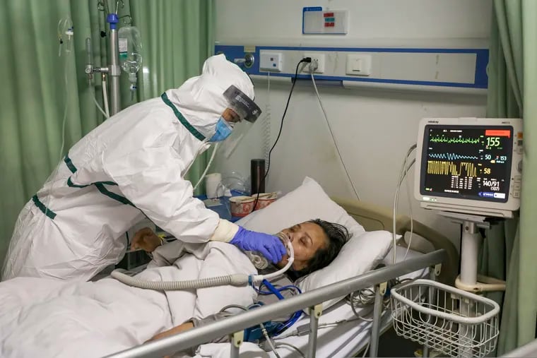 In this Thursday, Feb. 6, 2020, photo, a nurse feeds water to a patient in the isolation ward for 2019-nCoV patients at a hospital in Wuhan in central China's Hubei province. The number of confirmed cases of the new virus has risen again in China Saturday, Feb. 8, 2020, as the ruling Communist Party faced anger and recriminations from the public over the death of a doctor who was threatened by police after trying to sound the alarm about the disease over a month ago.