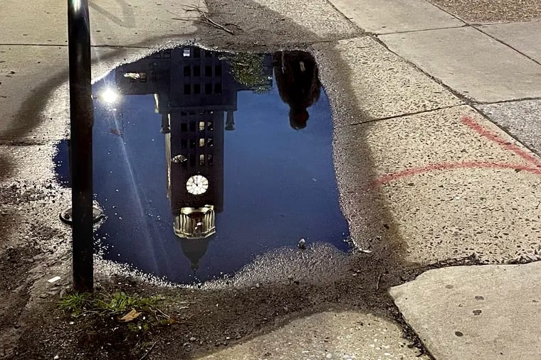 The Public Services Building,  headquarters of the Philadelphia Police Department and other offices, is reflected in a puddle along North Broad at Buttonwood Street. The historic eighteen-story Beaux-Arts style skyscraper and former Inquirer and Daily News building - until the newspapers moved out in 2012 - opened in 1925 as the Elverson Building and in 1996, was added to the National Register of Historic Places. Scene Through the Lens features staff photographer Tom Gralish’s visual exploration of our region. The same photo runs in both zones every Monday on B-2. This sentence runs at the end of the caption in print: More of photographer Tom Gralish’s visual exploration of our region can be seen in his blog at Inquirer.com/sceneontheroad