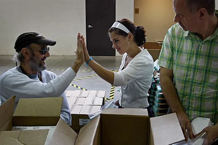Sarah Beck (center), 16, from the Coatesville Youth Initiative Service Corps, high-fives worker Mike Tratzer (left) while Steve Whitehead (right) watches. (Michael S. Wirtz / Staff Photographer)