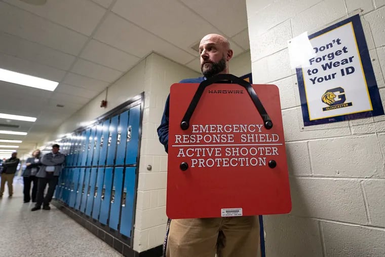Teacher Kevin Young holds a steel shield in the hallway at Gloucester City High School in Gloucester City, N.J. The shield is designed to protect students and teachers against gun violence.