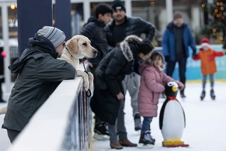 Glenn Elliott and his Labrador retriever “Dude” watch people ice skate at the Dilworth Park ice rink on Dec. 25. Though Christmas Eve and Christmas Day were bitter cold, a big warmup is on the way for New Year's Day.