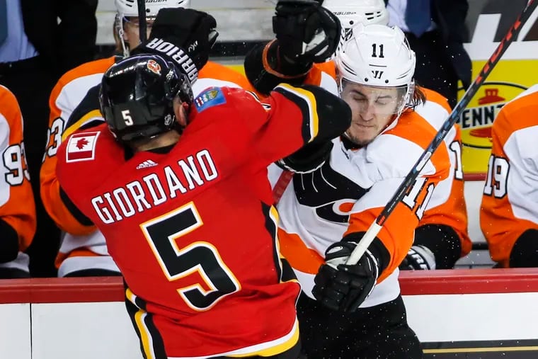 Travis Konecny (right) is checked by the Flames' Mark Giordano during Philadelphia's loss to Calgary on Wednesday.