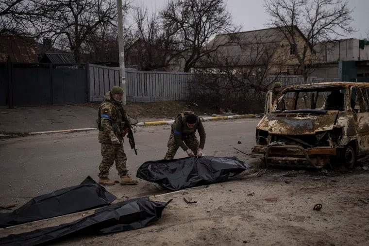 Ukrainian soldiers recovering the remains of four killed civilians from inside a charred vehicle in Bucha, outskirts of Kyiv, Ukraine, on Tuesday.