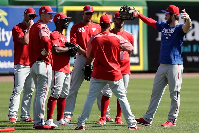 Bryce Harper talks with teammates during drills on Sunday in Clearwater.
