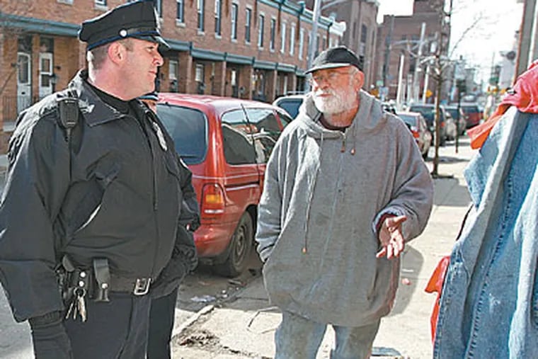Officer Brian McBride talks in Frankford with Chris O’Leary, whose neighborhood was the worst for crime, according to a Temple University study that shows foot patrols helped. (MICHAEL BRYANT / Staff Photographer)