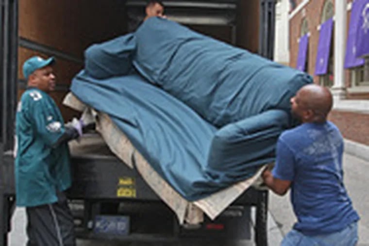 Bowens and Brown load a couch donated by the Obama campaign into a school district truck.
