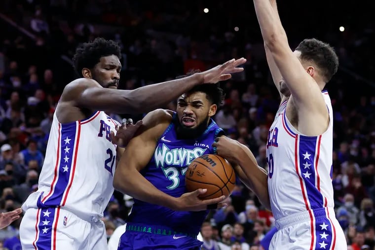 Minnesota Timberwolves center Karl-Anthony Towns drives to the basket defended by Sixers center Joel Embiid and forward Georges Niang.