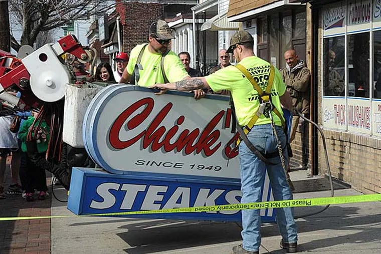 Scott Longacre (left) and James Chandler, workers from Pro Signs of Downingtown, lower the Chink's Steaks sign from the longtime steak shop on Torresdale Avenue as the restaurant changes its name to Joe's Steaks on April 1, 2013. Members of the Asian-American community urged the owner to remove the ethnic slur. (CLEM MURRAY / Staff Photographer)