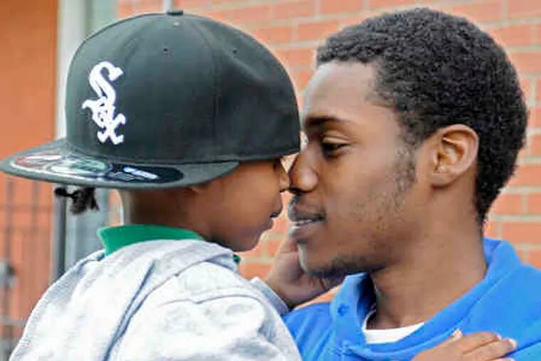 Kenny Woods, cleared in a fatal hit-and-run, holds son Za'khi, 4, outside their home on Aspen Street near 40th in West Philly.