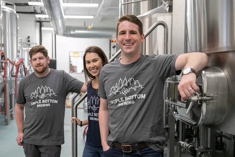 Bill Popwell, right, Tess Hart, and brewer Kyle Carney pose for a portrait inside the brewhouse at the new Triple Bottom Brewing in the Spring Garden section of Philadelphia on Friday, Sept. 13, 2019.