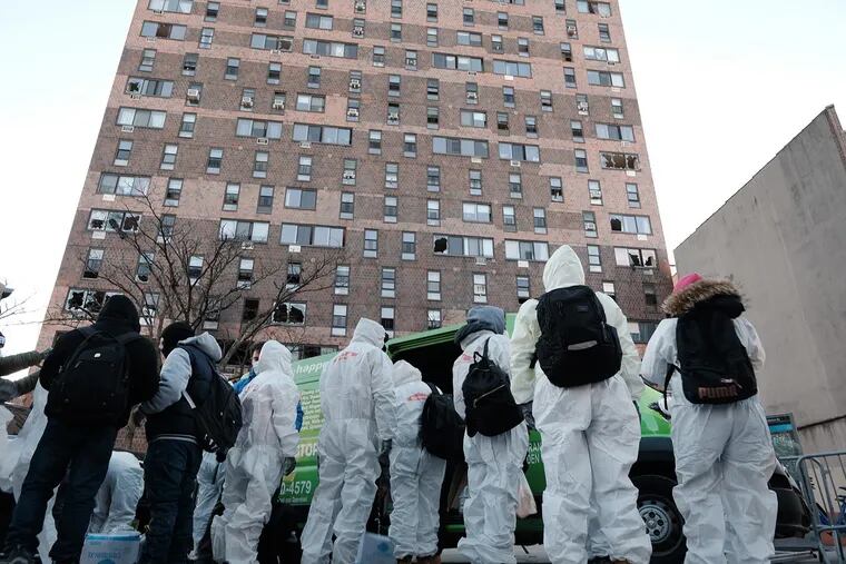 Clean-up and recovery workers gather in front of a Bronx apartment building a day after a fire swept through the complex killing 17 people and injuring dozens of others, many of them seriously, on Jan. 10, 2022, in New York City. (Spencer Platt/Getty Images/TNS)