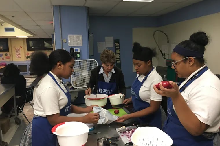 From left, Simran Singh, volunteer Margaret O'Neill, Sanaa Burton and Desire-e White prep ingredients for roasted chicken and vegetables at Gesu School in North Philadelphia.