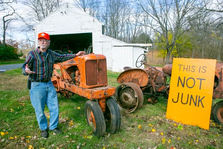 Gil Pringle next to his tractors in his lawn in Highland Twp., Pa., and a sign with "This is not junk" painted in bold, black letters to prove a point.