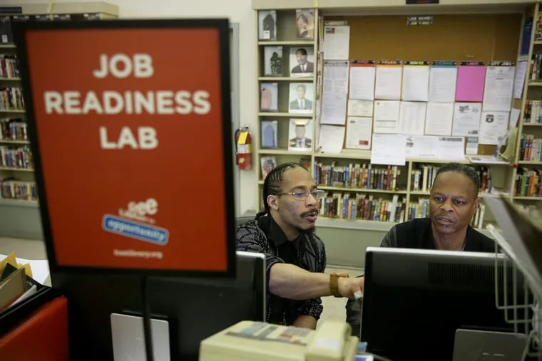 Digital resource specialist Omelio Alexander, left, helps Carl Haines apply to a job online at the Paschalville Library in Southwest Philadelphia on Friday, May 18, 2018. The branch is the only Free Library of Philadelphia location with a Job Readiness Lab, which helps community members find and apply to jobs.