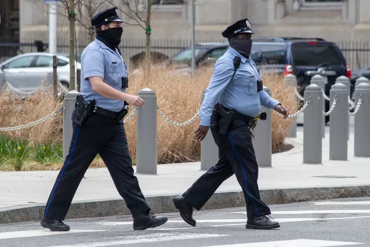 Philadelphia police officers cross a road on the east side of Philadelphia City Hall.