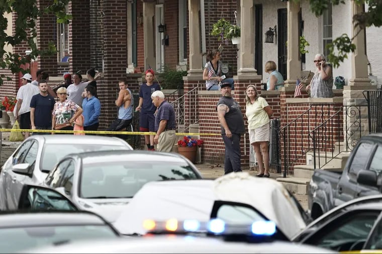 Neighbors look on as investigators gather at the crime scene on Hegerman Street near Princeton Avenue in the Tacony section of Philadelpia, Monday Aug. 20, 2018, after police fatal shot a man.