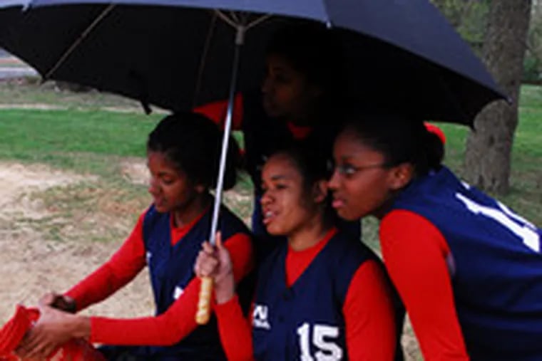 Huddled under an umbrella, (from left) Willingboro&#0039;s Jaleesa Davis, Theresa Pogue, Brittany Best and (rear) Vanessa Muse cheer on their team against Woodrow Wilson in the fifth inning of Wednesday&#0039;s softball game. Willingboro rained all over Wilson, 30-7.
