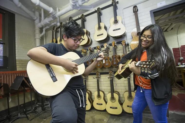 Former Home members Brandon Emigdio, left, and Maria Moreno play around on guitars before the screening of a documentary about their elementary school’s rock band.