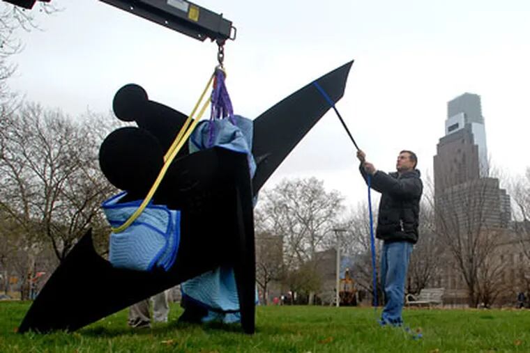 Eric McDade with Crozier Fine Arts helps remove the Alexander Calder sculpture "Three Discs, One Lacking (1968)," from it's place at 22nd and the Parkway on Wednesday.   (Tom Gralish / Staff Photographer)