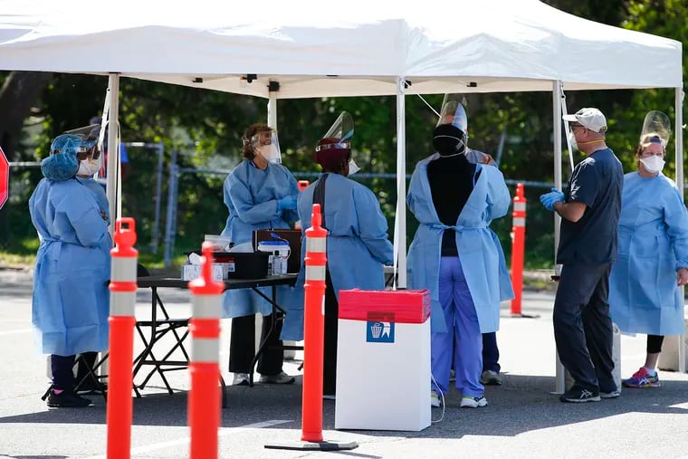 Medical workers prepare to conduct COVID-19 testing at a new drive-through and walk-up mobile testing site at Upper Darby High School in Delaware County on Thursday.