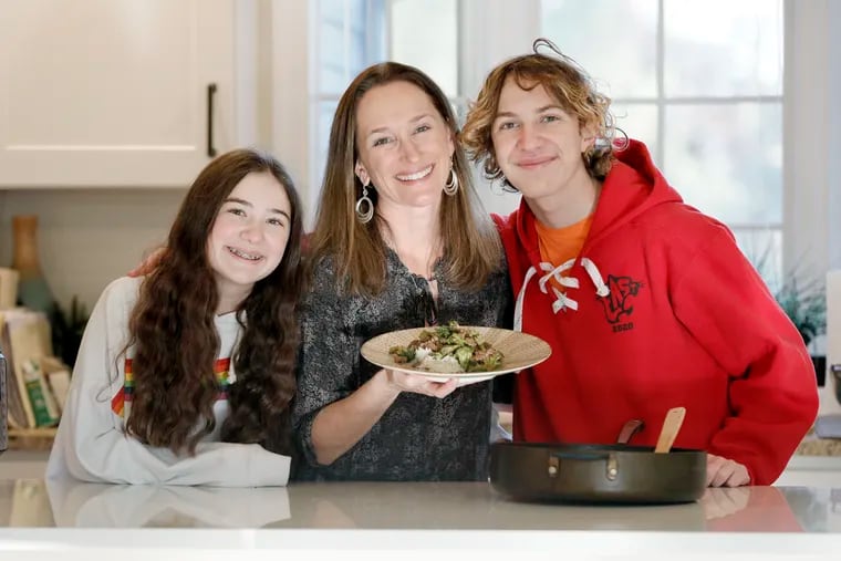 (L-R) Abigail Zinn, 13, Stephanie Zinn (mom) with her ground beef with broccoli and Cody Zinn, 16. Stephanie is among the coordinators and contributors to a cookbook called POTS AND PANDEMIC: COOKING IN QUARANTINE, that includes recipes and reflections about coping with the pandemic by getting busy in the kitchen. The book is a fundraising project of Temple M'kor Shalom in Cherry Hill. Zinn was photographed in Haddonfield, N.J.