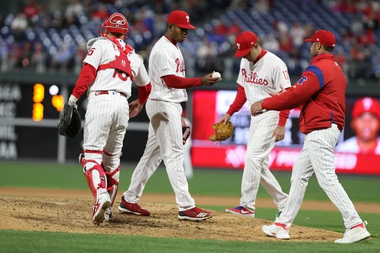 Edubray Ramos, 2nd from left, of the Phillies  hands the baseball to Manager Gabe Kapler, right, as he is removed from the game in the 7th inning against the Nationals at Citizens Bank Park on April 10, 2019.