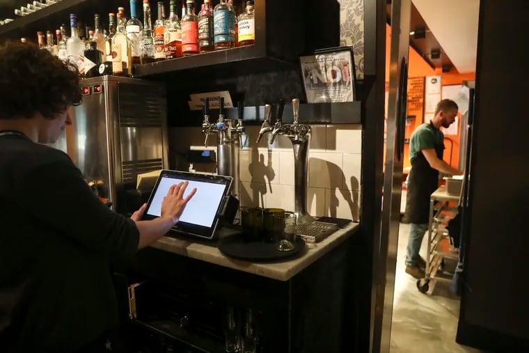 Wolf Williams, general manager of Abe Fisher restaurant, shows the point-of-sale system by the kitchen in Center City, Philadelphia on Tuesday, April 11, 2023.