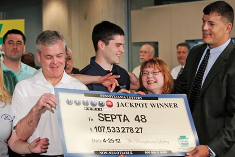 Lottery Executive Director Todd Rucci (right) presents the ceremonial check to the group of Powerball winners Friday morning at SEPTA headquarters at 1234 Market St. The group of 49 workers won the $107.5 million Powerball jackpot after buying their ticket in the Gallery near their offices. ALEJANDRO A. ALVAREZ / Staff Photographer