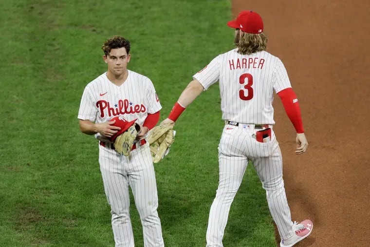 Scott Kingery getting a tap from teammate Bryce Harper after Kingery flied out against the Atlanta Braves on Aug. 8.