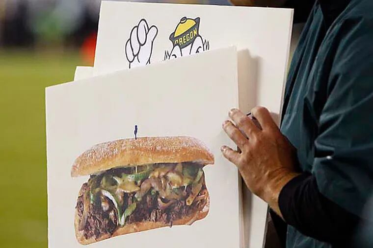 Eagles signal callers use signs, including a cheese steak, as the Eagles and Patriots play a preseason game at Lincoln Financial Field in Philadelphia. (David Maialetti / Staff Photographer)