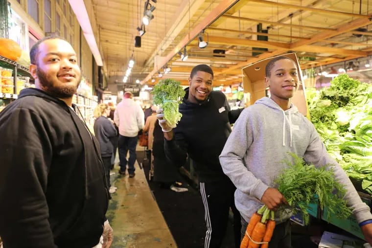 Blair Parham, Marquis Graham and Shaurice Fair help out at Iovine Produce during the Thanksgiving holiday rush at the Reading Terminal market on November 22, 2016.