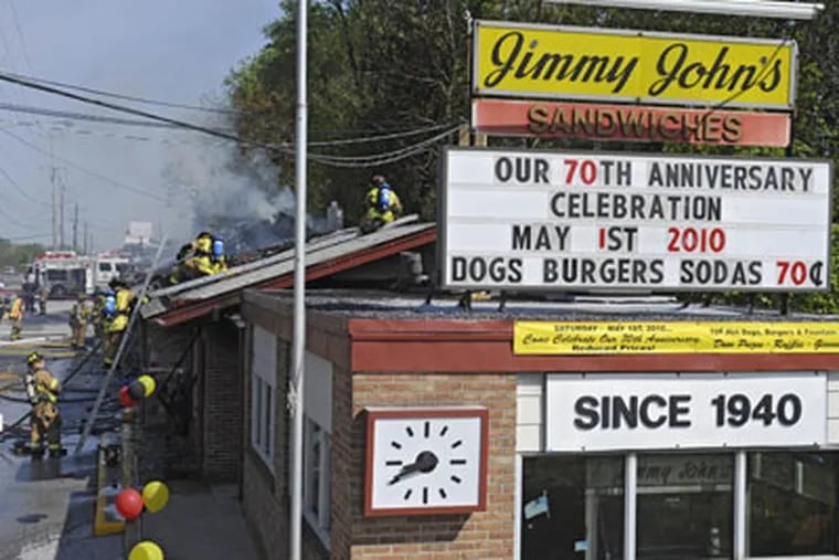 Firefighters swarm the roof of Jimmy John's, the landmark restaurant on Route 202 in Delaware County, which caught fire this morning as staff was getting ready to celebrate its 70th anniversary. ( Clem Murray / Staff Photographer )
