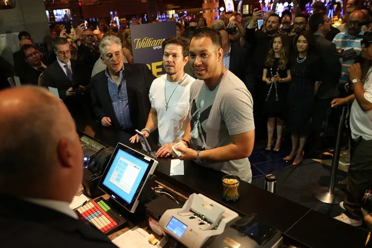 Mark Wahlberg, center, is joined by Bruce Deifik, left, chairman of Ocean Resort Casino, and Rick Martinez, right, who works for Wahlberg, as he places a bet at the new sports book during the grand opening of the Ocean Resort Casino in Atlantic City, NJ on June 28, 2018.