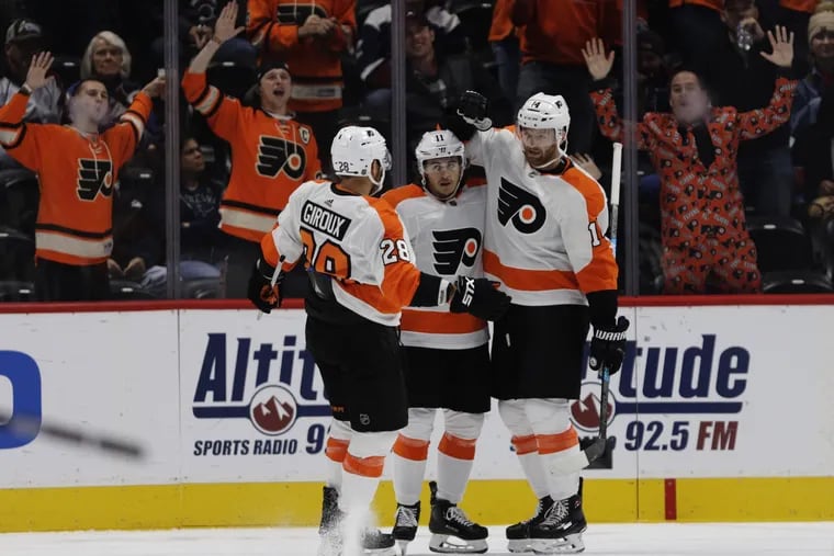 Flyers fans in Colorado join Claude Giroux (28) and Travis Konecny (11) celebrating a goal by Sean Couturier (right) against the Avalanche on Saturday.