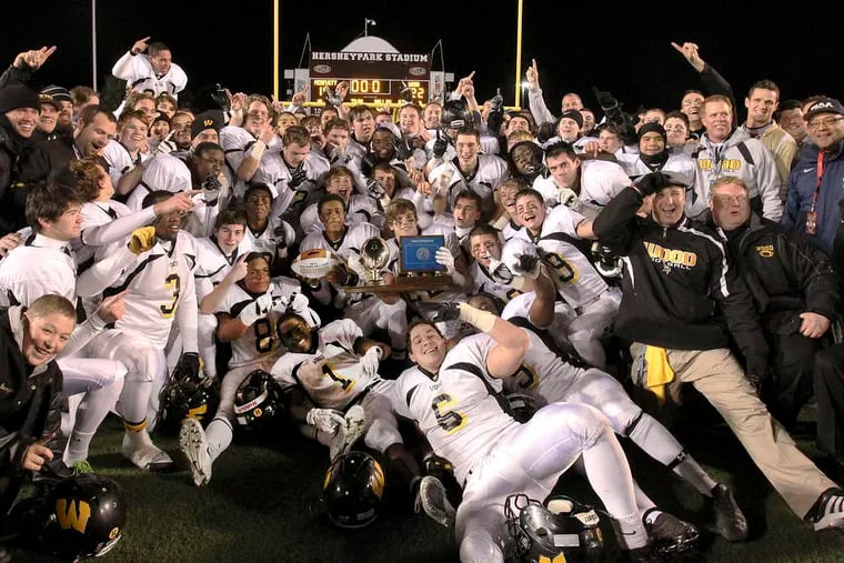 Archbishop Wood's players and staff gather around the state Class AAA championship trophy after their 22-10 triumph over Harrisburg's Bishop McDevitt. STEVEN M. FALK / Staff Photographer