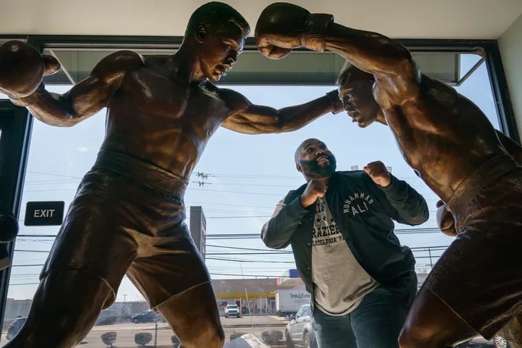 Derek Dennis Frazier, the youngest son of former World Heavyweight Champion Joe Frazier, with the sculpture created by artist Chris Collins. The piece depicts the legendary Joe Frazier-Muhammad Ali fight that took place on March 8, 1971.