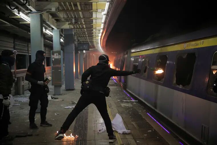 A student hurls a molotov cocktail into a train parked inside the Chinese University MTR station in Hong Kong, Wednesday, Nov. 13, 2019. Protesters in Hong Kong battled police on multiple fronts on Tuesday, from major disruptions during the morning rush hour to a late-night standoff at a prominent university, as the 5-month-old anti-government movement takes an increasingly violent turn.